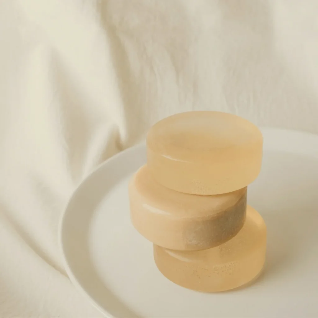 白い皿に３つ重ねられた透明石鹸。柔らかな光と静かな余白のあるイメージ。