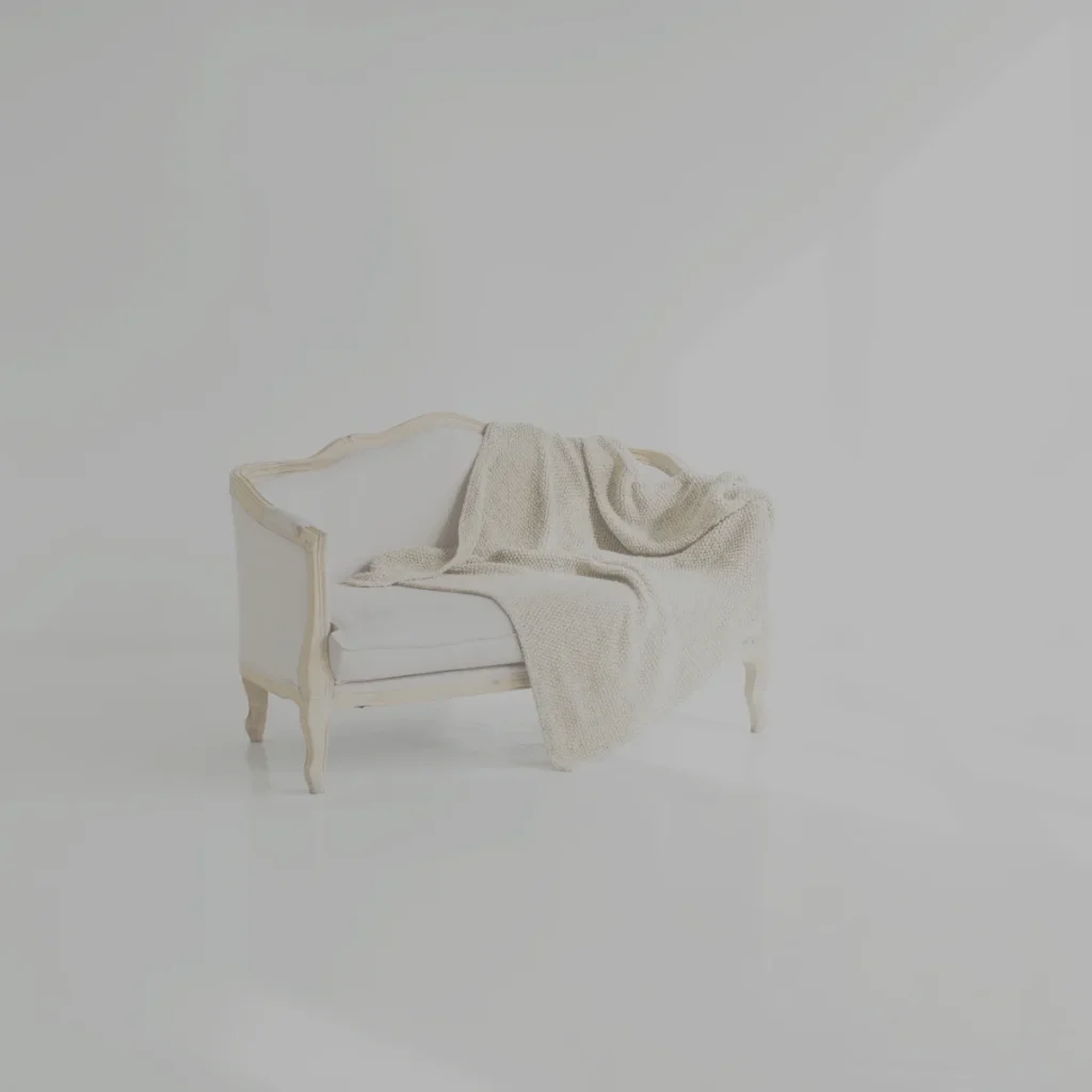 柔らかな光が差し込む部屋で、ソファにかけられたブランケットが落ち着きを感じさせるイメージ。