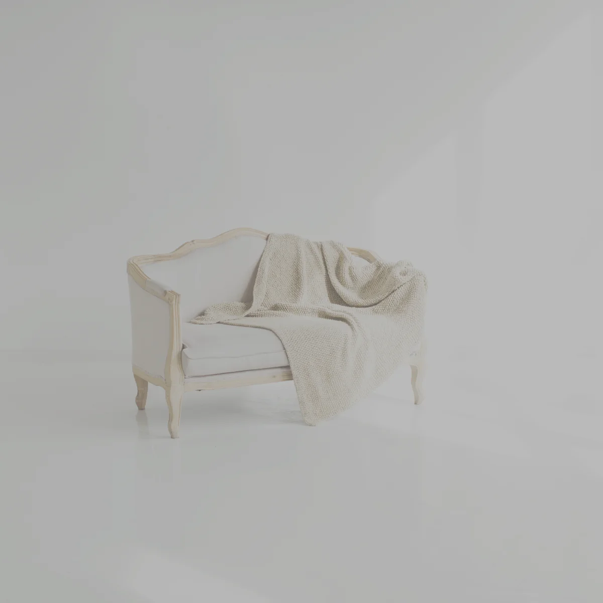 柔らかな光が差し込む部屋で、ソファにかけられたブランケットが落ち着きを感じさせるイメージ。